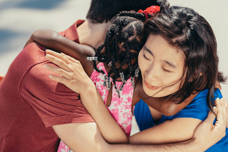 A diverse family of three sharing an emotional group hug, symbolizing the successful legal process of adoption in the Philippines.