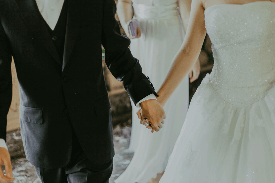 Close-up of a bride and groom in wedding attire holding hands, representing the legal bond of marriage and Family Law proceedings.