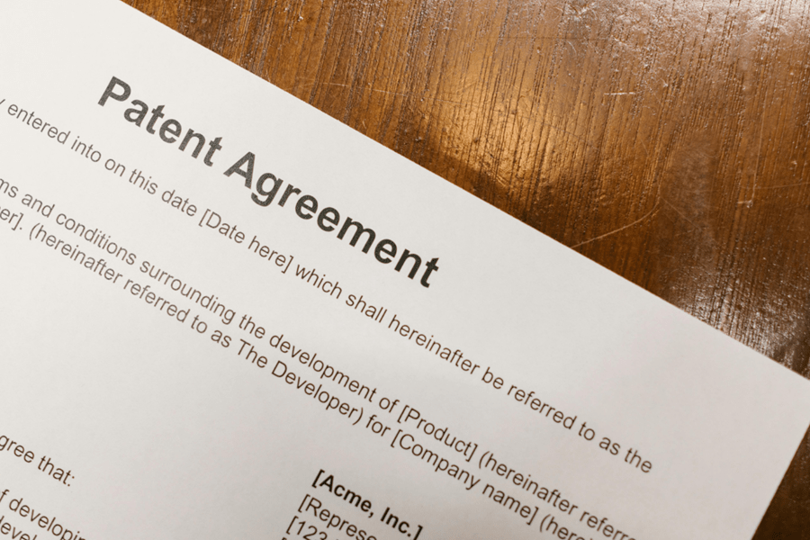 Close-up of a Patent Agreement document on a wooden desk, highlighting legal protection for inventions and intellectual property.