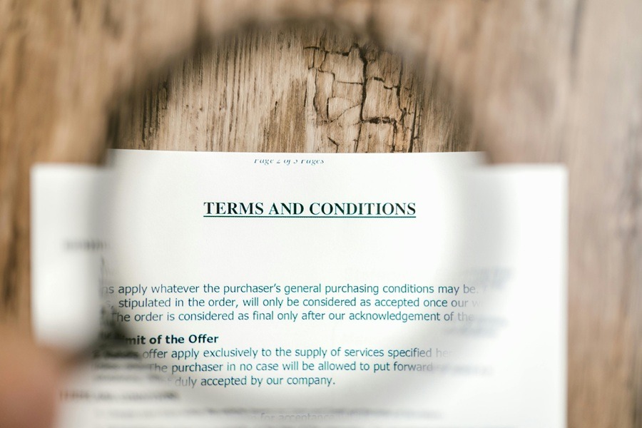 A magnifying glass focused on the "Terms and Conditions" section of a legal contract.