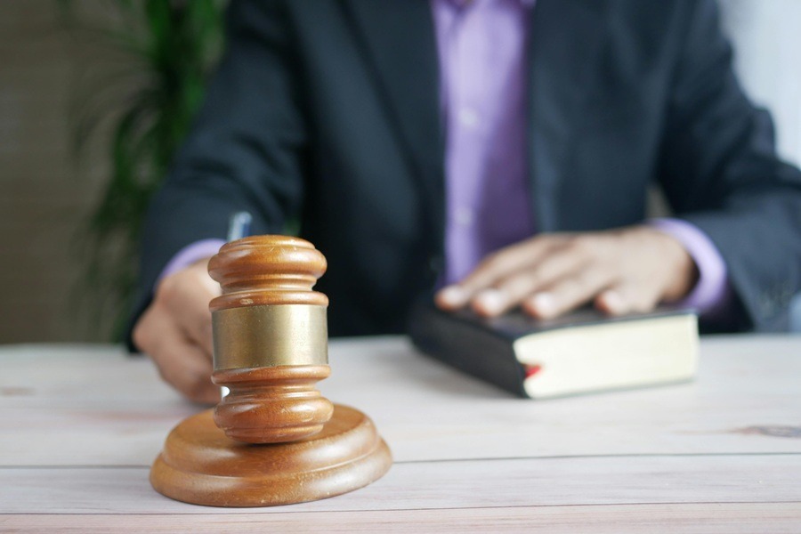 Professional legal gavel resting on a wooden desk next to a law book in a law office