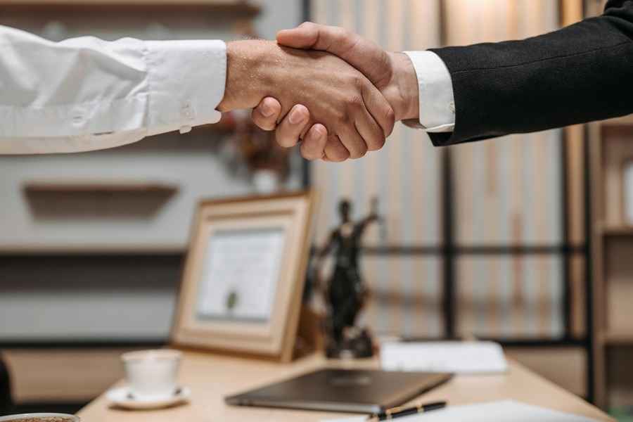 Lawyer and client shaking hands over a desk in a law office to finalize a retainer agreement